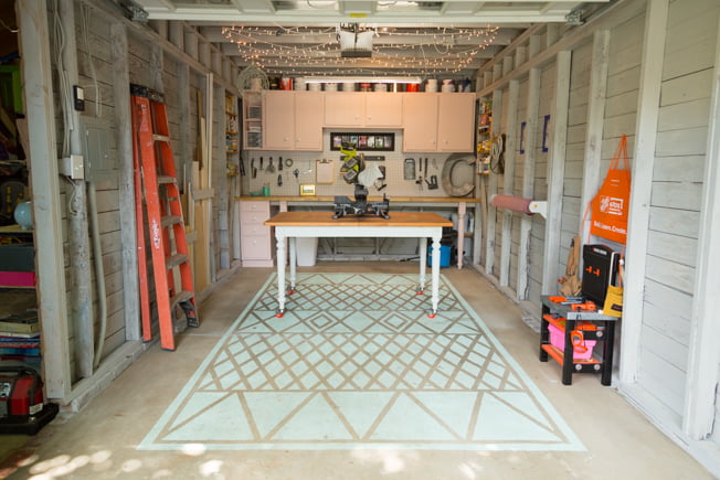 El taller de Chelsea Lipford Wolf, con una mesa de trabajo, una alfombra de hormigón pintado, un tablero de clavijas y armario rosas y un banco de trabajo.