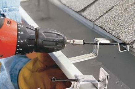 Trabajo con un destornillador durante el montaje de las canaletas. Trabajador durante el montaje de los canalones