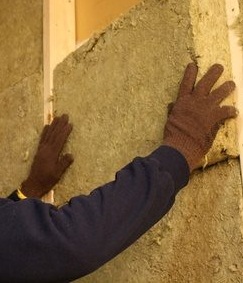 Un artesano que instala aislamiento acústico  Un artesano mientras coloca un aislamiento acústico.