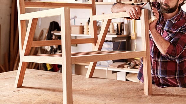 Diseñador de muebles lijando el marco de una silla de madera