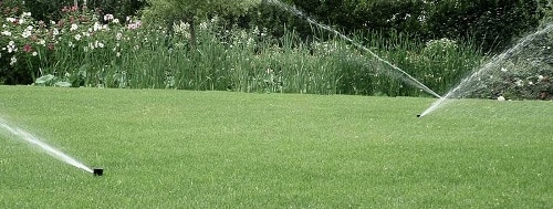 Un hermoso césped mientras el riego está en curso Un césped mientras el riego está en curso